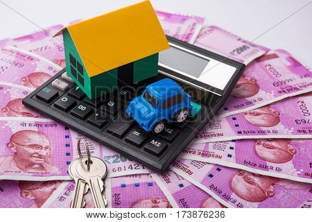 indian real estate or residential model house with new currency notes, keys, toy car and calculator, selective focus