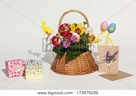 Easter composition. Bright Easter composition of bouquet in basket colored boxes cards and eggs.