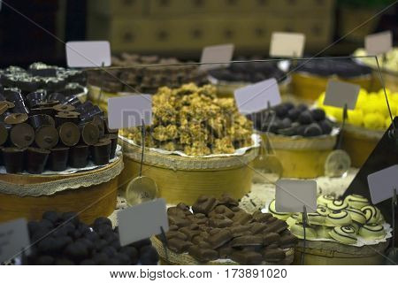 Large selection of chocolates on counter of market store in dark room. Wide assortment of candy, selective focus