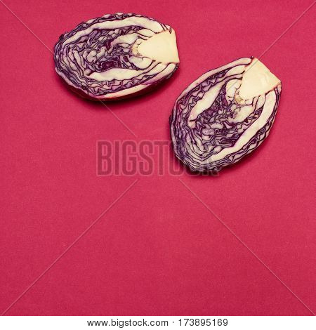 The fresh red cabbage cut in half on a red background