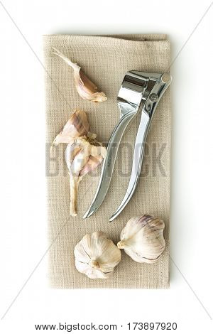 Garlic and garlic press on napkin isolated on white background.