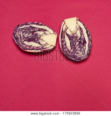 The fresh red cabbage cut in half on a red background