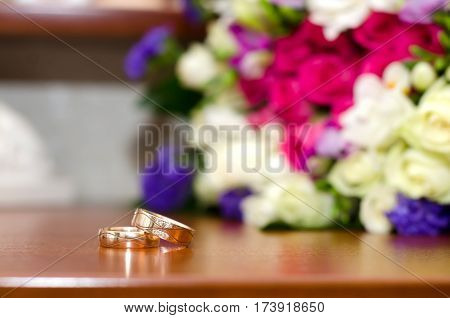 Bright picture with wedding rings and colorful wedding bouquet on the table