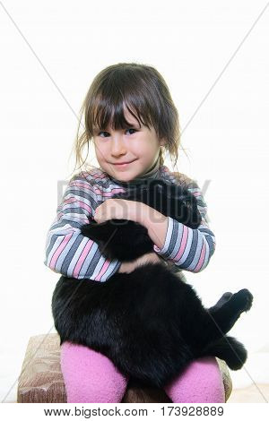 Happy little girl hugging lovely kitten. Cute child playing with her cat, isolated on white background