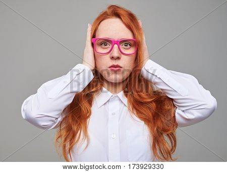 Close-up of frustrated young red hair teenager covering ears with hands and keeping eyes open.  Do not want to hear anything 