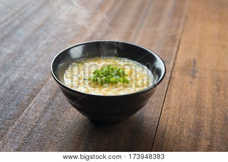 Asian style congee bowl on wooden table background.