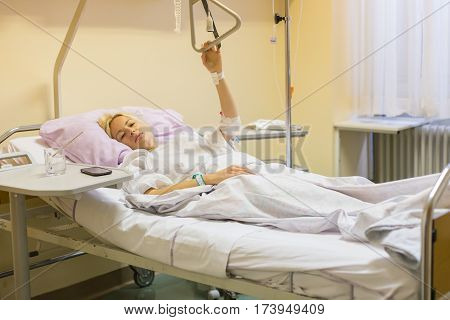 Bedridden female patient lying in hospital bed, recovering after surgery.