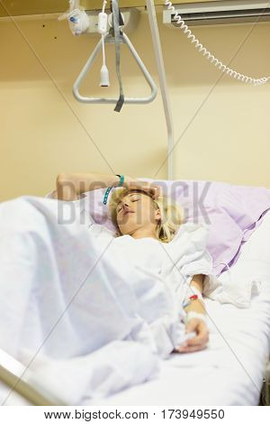 Bedridden female patient lying in hospital bed, recovering after surgery.