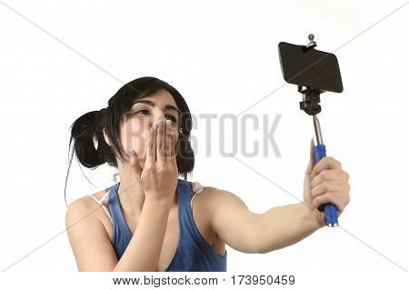 young attractive and sexy woman taking selfie photo with stick and mobile phone camera posing happy and playful sending kiss isolated on white background in shooting self portrait
