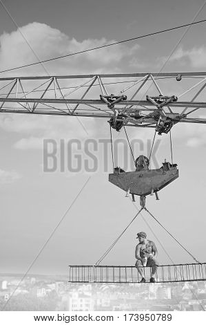 Peaceful heights. Vertical monochrome shot of a retro dressed builder sitting on a crossbar above the city having lunch copyspace heights fearless confidence worker building construction crane food