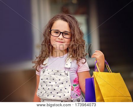cute little girl with shopping bags walking in the city