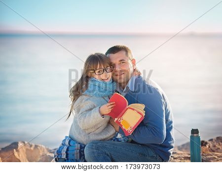 Father reading a book to his daughter outdoors