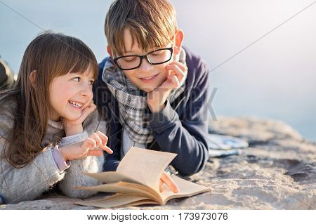 portrait of cute Children reading a book outdoors