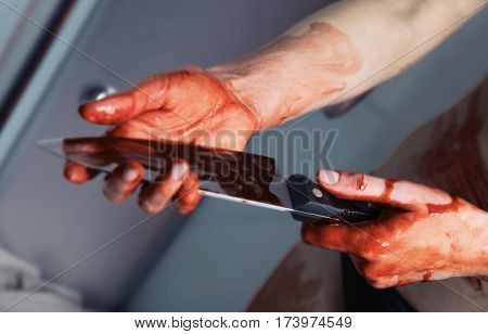 Bloody hands with knife of depressed woman in shower