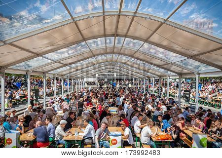 Many people together outdoors eating and drinking.
Stockholm, Sweden - June 07, 2013: People gathered together in open tent at public square. Eating and drinking outdoors at annual food event in Stockholm June 07, 2013.