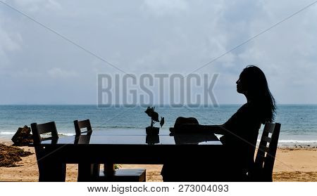 Single Asian Young Woman Sitting At Dining Table On Beach