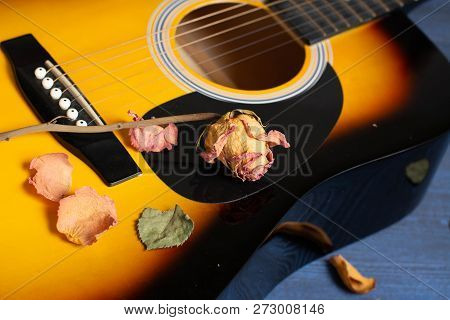 Acoustic Guitar With Dried Roses On The Wooden Table. Template For Advertising A Concert Of Memory O