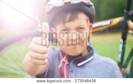 Riding Is Super. Portrait Of Smiling Teenager Riding Bike And Giving Thumbs Up On Background Of Park