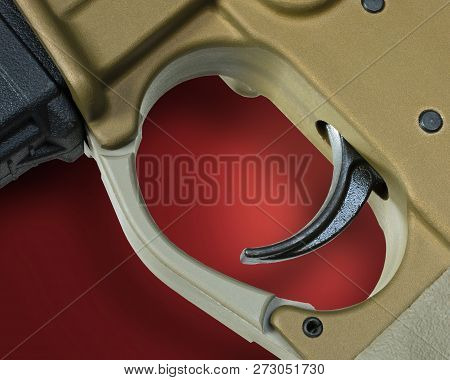 Trigger On A Copper Colored Ar-15 With Red And Its Shadow Behind