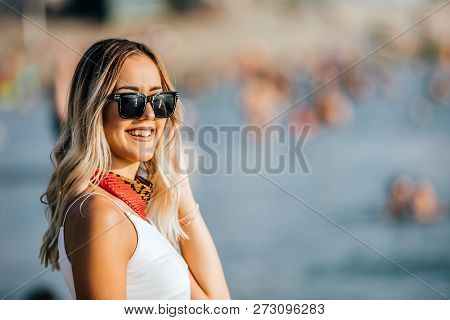 Smiling Woman With Sunglasses Standing At The Beach