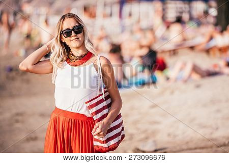 Woman With Sunglasses And Bag Walking On Sand Beach