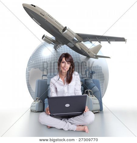 Giovane Bruna seduta con un computer portatile con una terra un aereo decollare e un mucchio di bagagli in b