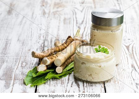 Spicy  Horseradish Sauce In Glass Jar On Wooden Table