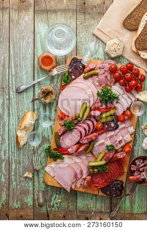 Assorted Sausages And Smoked Meat With Pickles, Bread And Vodka On Wooden Board, Top View Copy Space