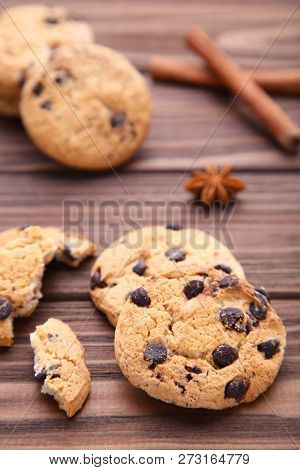 Delicious Chocolate Cookies On Brown Background. Chocolate Cookies And Cinnamon Sticks.