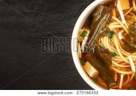 A Closeup Of A Bowl Of Miso Soup With Tofu, Scallions, Udon Noodles, Wakame, And Enoki Mushrooms, Sh