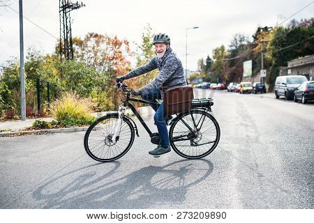 Active Senior Man With Electrobike Cycling Outdoors In Town.