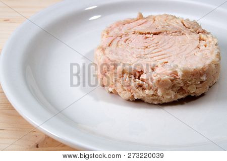 Solid White Albacore Tuna Fish Up Close On White Plate Still Shaped Like The Can It Came In On Woode