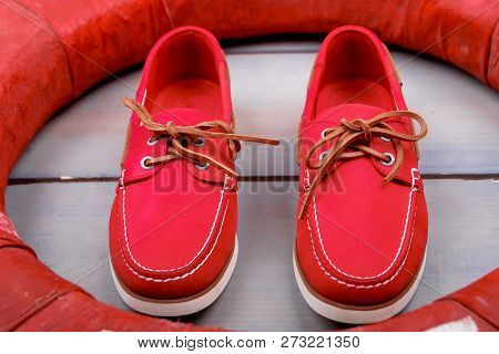 Red Boat Shoes On Wooden Background Near Lifebuoy. Top View. Close Up