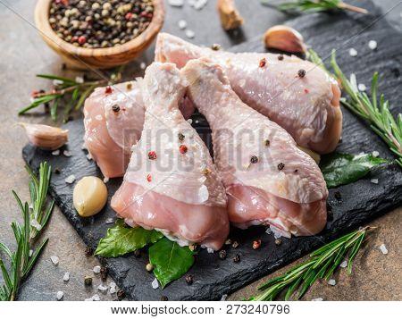 Chicken legs with spices and salt  ready for cooking on cutting board.