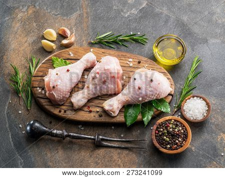 Chicken legs with spices and salt  ready for cooking on cutting board.