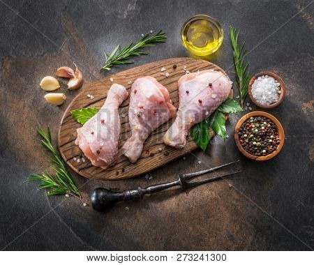 Chicken legs with spices and salt  ready for cooking on cutting board.