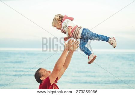 Father Picking Up Smiling Toddler In The Park