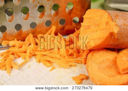 Fresh Carrot Grated On A Metal Kitchen Grate. Vegetables Prepared For Salad With A Meal On The Kitch