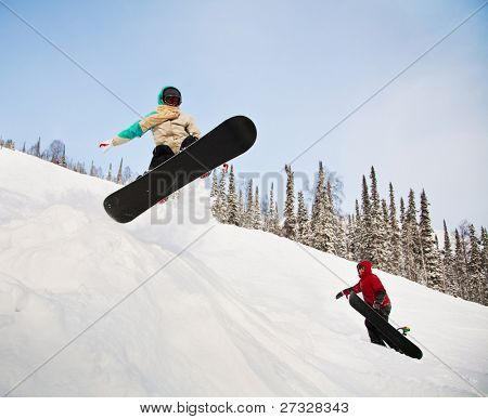 Snowboardista skoky vzduchem s tmavě modrou oblohou v pozadí