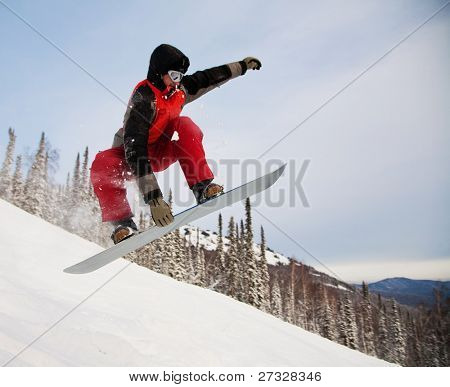 Snowboardista skoky vzduchem s tmavě modrou oblohou v pozadí