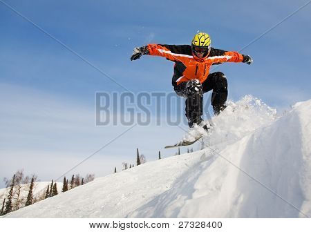 Snowboardista skoky vzduchem s tmavě modrou oblohou v pozadí