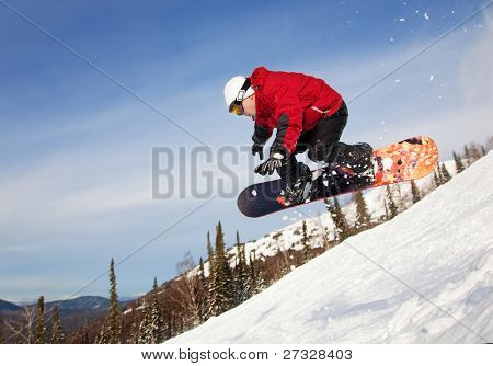 Snowboardista skoky vzduchem s tmavě modrou oblohou v pozadí