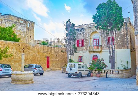 The Small St. Agatha Square In Mdina Fortress With Small Fountain And Mansion With Red Windows And T