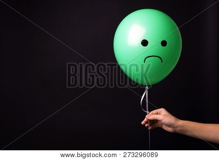 Woman Holding Balloon With Sad Face On Black Background, Space For Text. Threat Of Depression