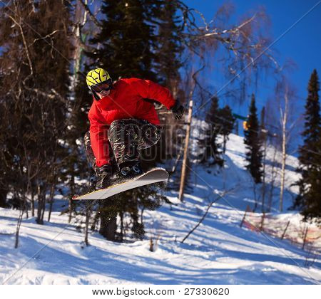 Snowboardista skoky vzduchem s tmavě modrou oblohou v pozadí