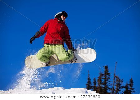 Snowboardista skoky vzduchem s tmavě modrou oblohou v pozadí