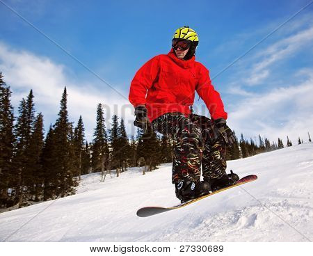 Snowboardista skoky vzduchem s tmavě modrou oblohou v pozadí