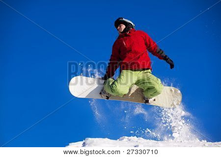 Snowboardista skoky vzduchem s tmavě modrou oblohou v pozadí