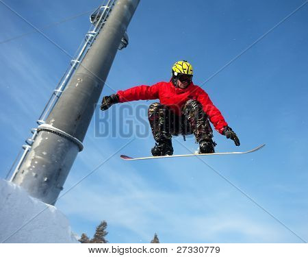 Snowboardista skoky vzduchem s tmavě modrou oblohou v pozadí