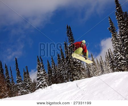 Snowboardista skoky vzduchem s tmavě modrou oblohou v pozadí